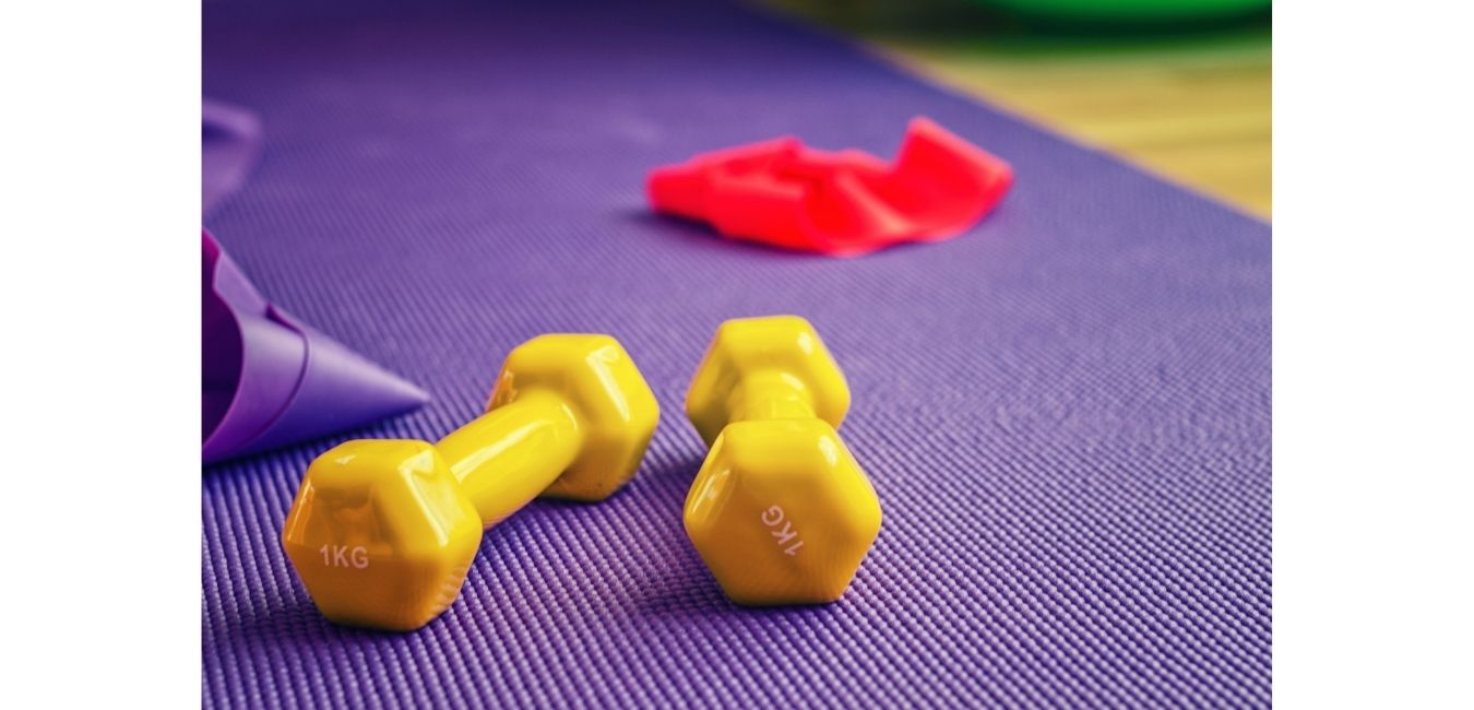 żółte hantle kolorowe na fioletowej macie do ćwiczeń z gumami do treningu